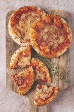 Four pizzetta Margaritas, on a cutting board, on a light gray surface, top view