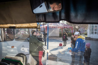 Two couples kiss in front of the departure of a bus leaving the Crimean peninsula, Simferopol,