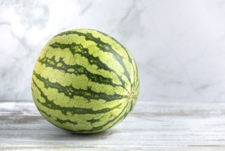 Watermelon on a wooden surface against a marbled background