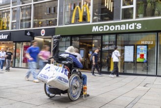 A man in a wheelchair in the Königstraße pedestrian zone in front of a branch of the McDonald's