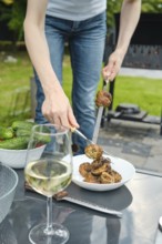 Unrecognizable woman put grilled champignons in a plate with a fork