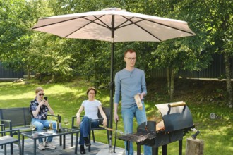 A family gathered in the backyard near a weekend barbecue