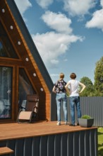 Rear view of mother and daughter standing on terrace of tiny house