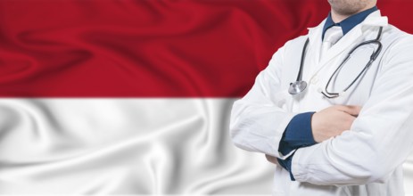 Monaco healthcare concept. Male doctor on Monaco flag. Doctor with crossed arms on Monaco flag