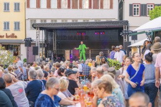 A man on stage entertains a large audience at an outdoor event, 950 years Weil der Stadt ceremony,