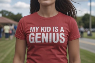 Close-up of woman wearing red t-shirt with text My Kid is a Genius outdoors. Concept of parental