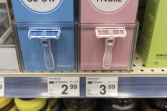 Close-up of blue and pink disposable razors with different prices. Visual representation of the
