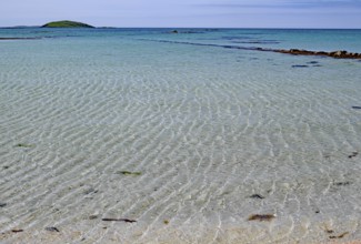Clear bright blue beach with gentle waves under a cloudless sky, Outer Hebrides, Eriksay, Scotland,