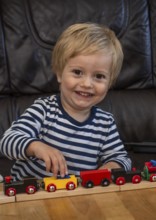 Blond boy, 2 years old, playing with toy train in Ystad, SkÃ¥ne County, Sweden, Scandinavia