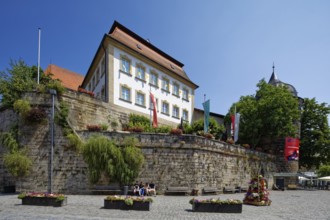 Marienplatz cobbled, flower pots, town wall, above catholic parish office St. Johannes, on the