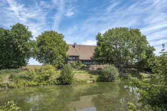 A house on the banks of the river Stever, surrounded by trees under a blue sky, MÃ¼nsterland, North