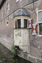 Medieval bay window on a brick wall with red shutters and moat, Raesfeld Castle, MÃ¼nsterland,
