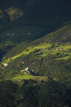 View of the Sonnenberg with Annenberg Castle and the farms above in the evening light, Dolomites,