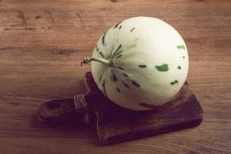 Dino melon, white with green stripes, small size, on the table, close-up, no people