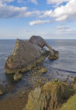 Remarkable rock formation jutting into the sea under a blue sky with few clouds, Bow Fiddle Rock,