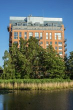 Newly (2025) built apartment building rising above the trees and behind a pond in Ystad, SkÃ¥ne