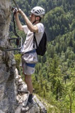 Mountaineer climbing over a steep ladder in the Isidor via ferrata, GrÃ¼nstein, Schönau am