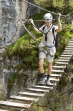 Mountaineer climbing over a suspension bridge on the Isidor via ferrata, GrÃ¼nstein, Schönau am