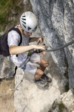 Mountaineer climbing over a steep wall in the Isidor via ferrata, GrÃ¼nstein, Schönau am Königssee,