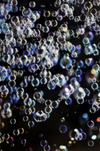 Many, small iridescent and floating soap bubbles against a black background, Recklinghausen, North