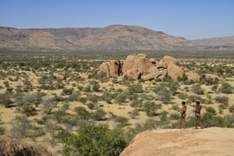 Two Bushmen with bows and arrows overlooking the landscape from a rocky hill, Erongo Mountains,
