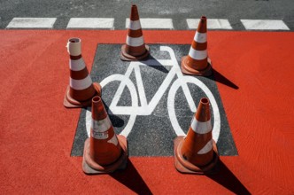 Warning cones standing on a cycle path sprayed with a stencil Symbol on a newly built cycle path,