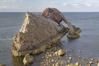 A large rock with a natural arch by the sea, surrounded by water, Bow Fiddle Rock, Aberdeenshire,