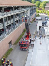 Fire engine and workers at a building with a lifting platform in an urban environment, fire brigade