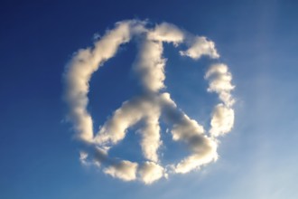 Peace sign made of white clouds floats in a clear blue sky, symbolizing harmony and hope.