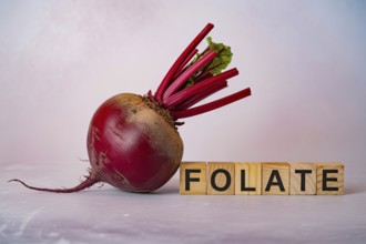 Crimson beetroot with wooden blocks spelling Folate. Studio composition showcasing natural