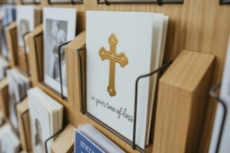 Condolence card with In your time of loss text and golden religious cross displayed in a card rack