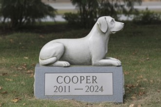 Gravestone with dog stone sculpture in a peaceful cemetery. Memorial for a beloved pet and pet loss