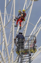 Firefighters on a rescue mission on a Ferris wheel with crane support, fire brigade exercise for