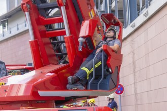 Firefighter relaxing on a lifting platform near a building, fire brigade exercise for gondola
