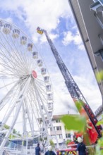 Rescue workers on a lifting platform next to a Ferris wheel in good weather, fire brigade exercise