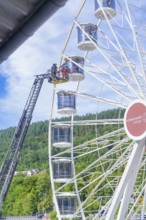 Firefighters carry out a rescue operation in a Ferris wheel standing in a green environment, Fire