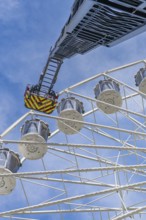Fire brigade ladder reaches up to the Ferris wheel, ready for an operation in the clear sky, fire