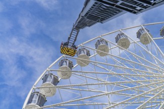 Fire brigade ladder extends to the cabins of the Ferris wheel, clear sky in the background, fire