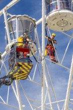 Worker with safety equipment during maintenance work on a Ferris wheel, fire brigade exercise for