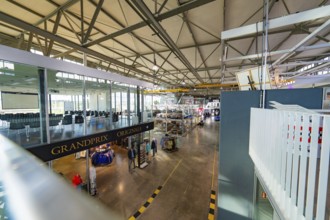 Large industrial hall with exhibited vehicles, modern architecture and bright lighting, Motorworld,