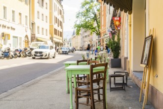A street café with green wooden chairs in sunny weather in a lively town, Merano, South Tyrol,