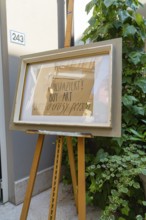 Artwork on easel next to a plant in front of a grey wall, Merano, South Tyrol, Italy