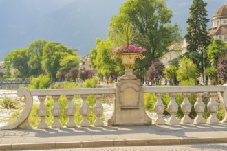 Decorative stone bridge with flower pot on the riverbank on a sunny day, Merano, South Tyrol, Italy