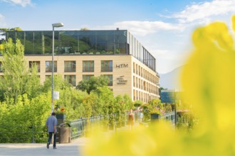 Modern hotel view in summer with plants, bright architecture and people walking, Merano, South