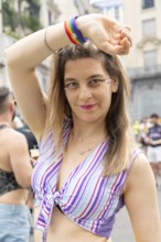 Young woman proudly wearing a rainbow wristband and sparkling glitter makeup, posing joyfully