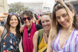 Four women smiling and posing together in a demonstration for women's rights, wearing sunglasses