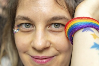 Woman celebrating pride month, wearing a vibrant rainbow bracelet and sparkling glitter makeup on