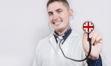 Doctor showing stethoscope with Georgia flag. Georgia national healthcare concept