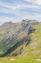 Steep mountain range with green slopes and striking sky in the background, Schlehrn hike, Alpe di