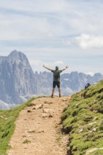 Person on a path with outstretched arms in front of a majestic mountain landscape, Schlehrn hike,